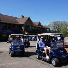 Golfers driving carts take off from the clubhouse