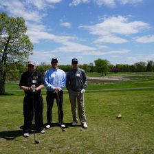 Three golfers pose in Tee Box