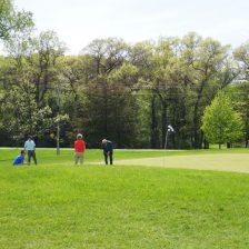 Foursome putting on the green